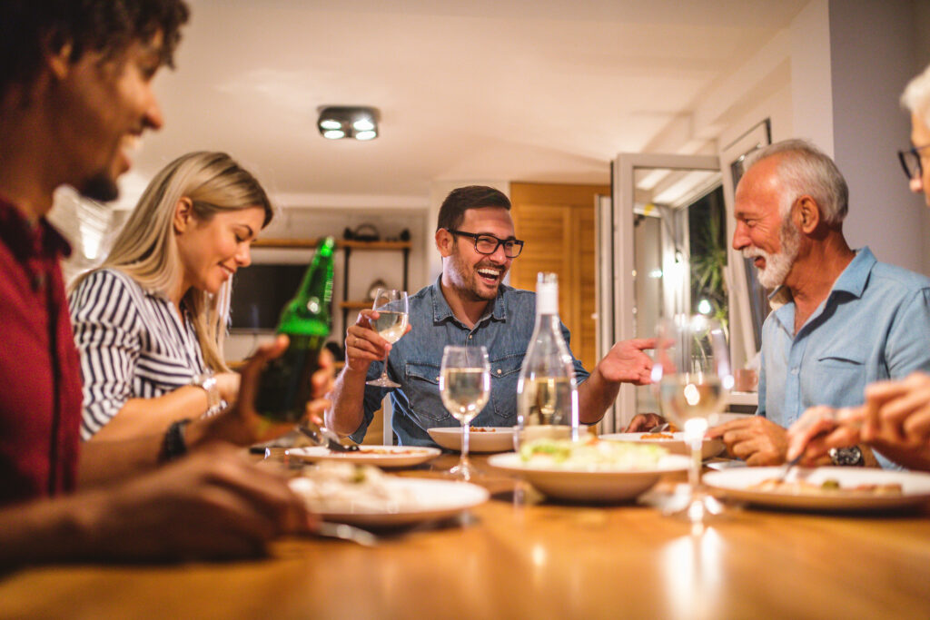 Neighbors gather around a table with lights in the home powered by a whole home backup Generac generator by Generator Supercenter.