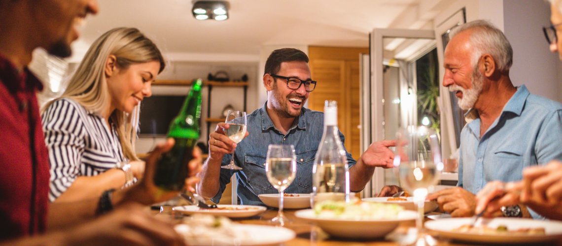 Neighbors gather around a table with lights in the home powered by a whole home backup Generac generator by Generator Supercenter.